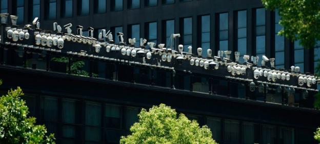 Numerous security cameras mounted on a building rooftop.