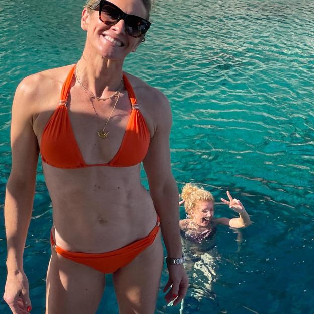 Gabby Logan in an orange bikini with another woman swimming behind her.