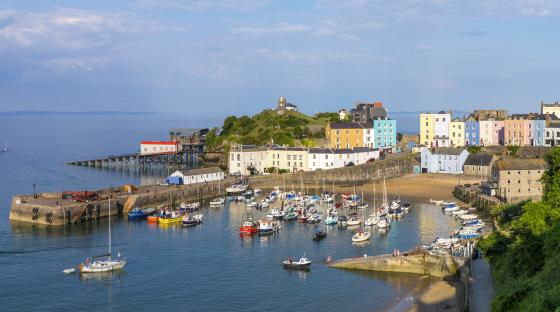 Tenby harbor in Pembrokeshire, Wales, with colorful buildings and many boats.