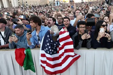 Crowd holding up an American flag and using cell phones.