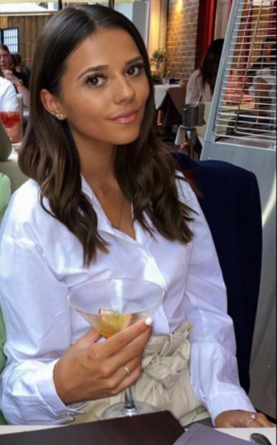 Woman holding a cocktail at an outdoor restaurant.