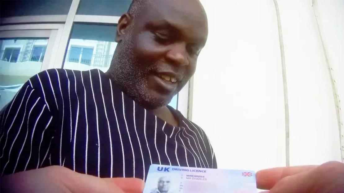 Man holding up a UK driving licence.