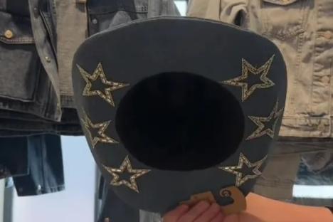 Denim hat with star embellishments held in a store.
