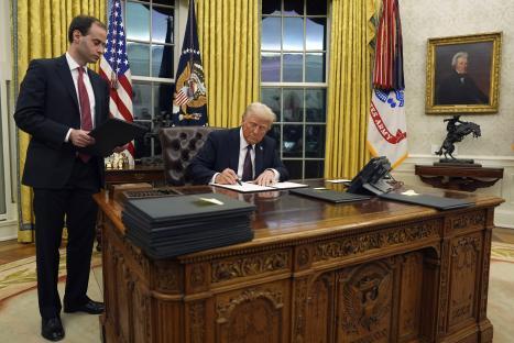 President Donald Trump signing an executive order in the Oval Office.