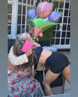 Daughter hugging mother with birthday balloons and card.