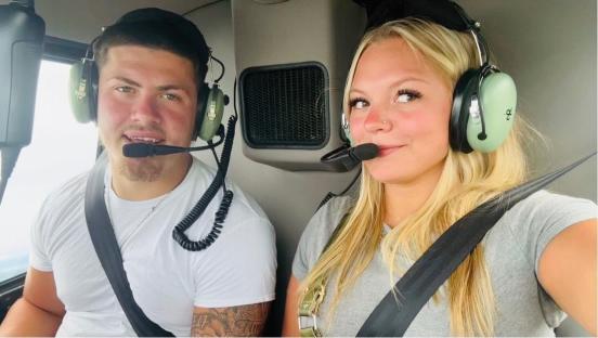 A man and woman wearing headsets in a helicopter.