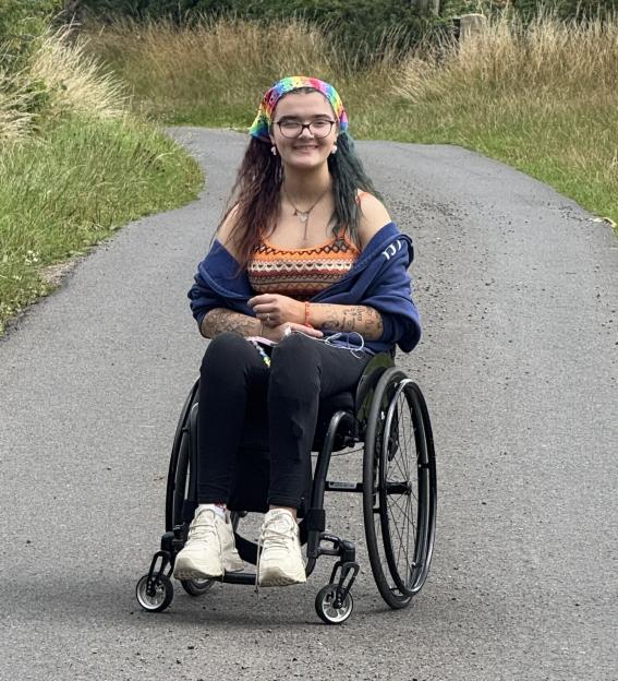 Young woman in wheelchair smiling on a path.