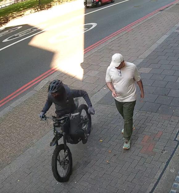 CCTV footage of a phone theft: a man on an electric bike snatches a phone from a pedestrian.