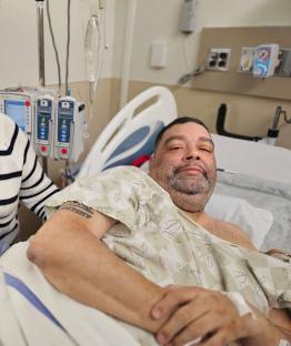 Man in hospital gown in hospital bed.