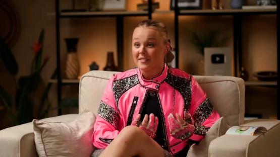 JoJo Siwa in a pink jacket during an interview.