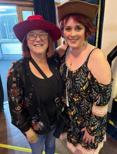 Photo of two women wearing hats and floral dresses.