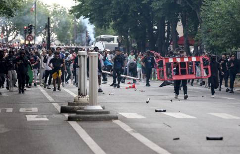 Crowd clashing with police officers in a street.