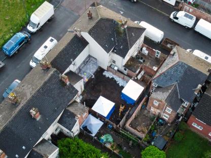 Aerial view of a crime scene with police vehicles and forensic tents.