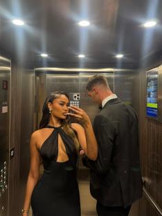 Ella Thomas and a man in formal wear taking a selfie in an elevator.