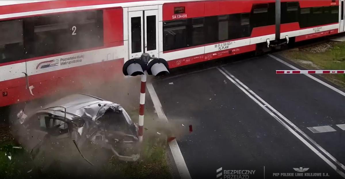 Car colliding with train at railway crossing.