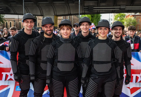 Group of performers in black light-up suits and helmets.