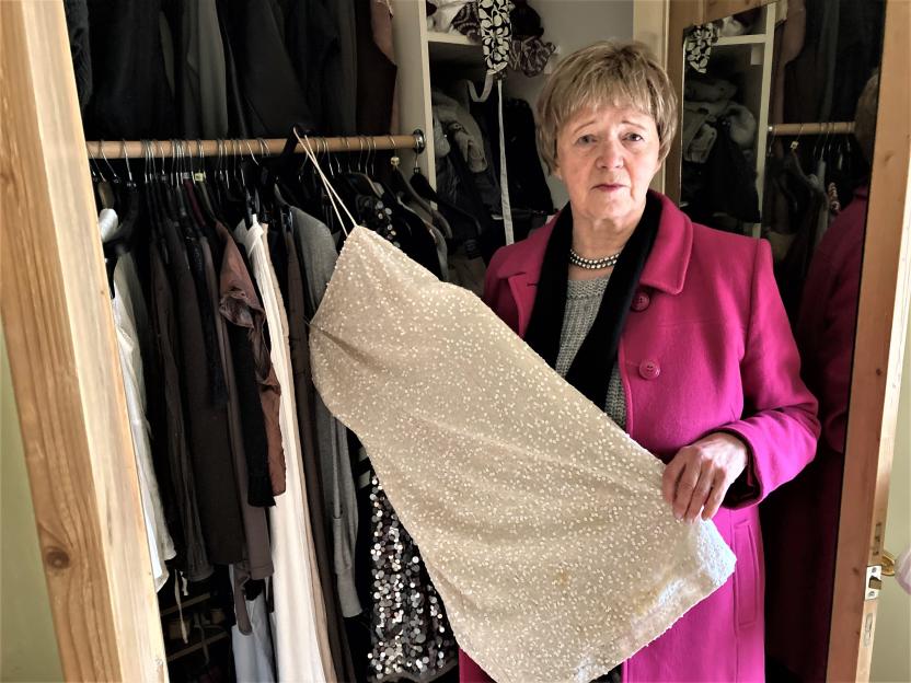 Joan Lawrence holding a sequined dress in front of her missing daughter's closet.