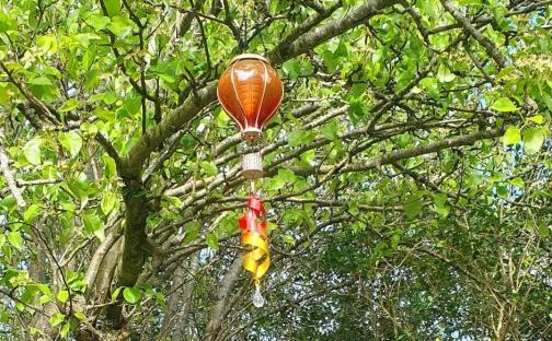 Hot air balloon garden decoration hanging from a tree.