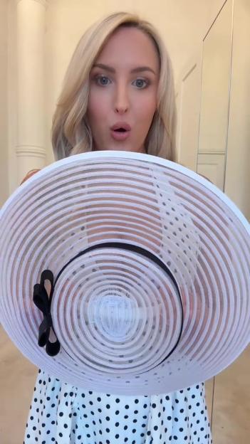 Woman holding a large white hat.