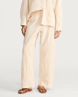 Beige pants and shirt with floral embroidery.