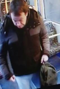 Man on bus holding hat.