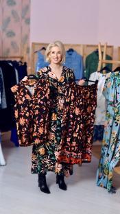 A celebrity stylist holds up two floral dresses.