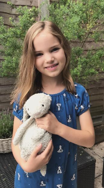 Emily smiling and holding a stuffed bunny.