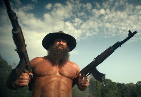 Brian Johnson in Untold: Liver King, holding two rifles.