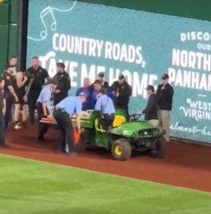Injured baseball fan being carried off the field on a stretcher.