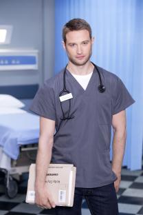 Dr. Caleb Knight, a Casualty doctor, holding patient files.