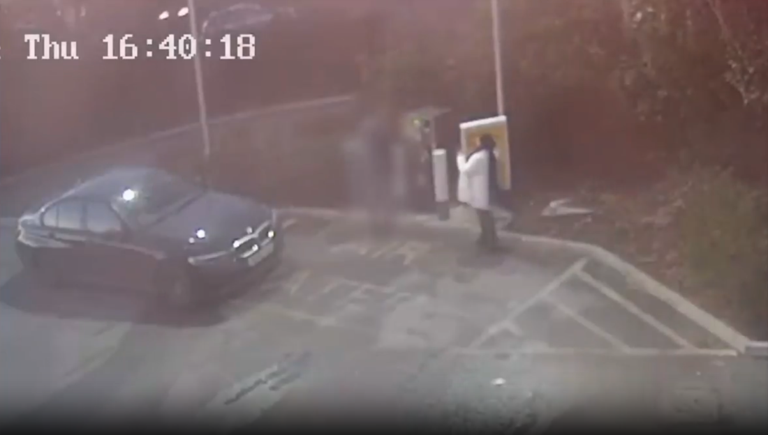 Security camera footage showing a person spray-painting a black car.