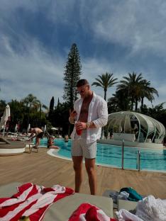 Man at a resort pool looking at his phone.