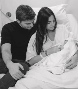 Black and white photo of a couple holding their newborn baby in a hospital bed.