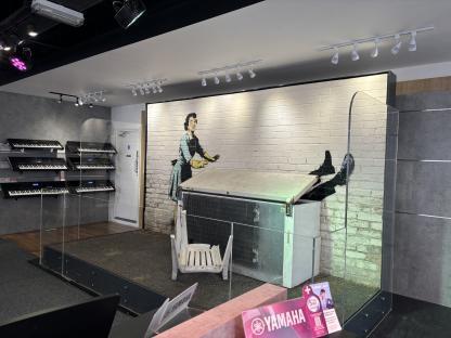 Banksy mural of a woman closing a freezer with a man's legs sticking out, displayed in a music store.