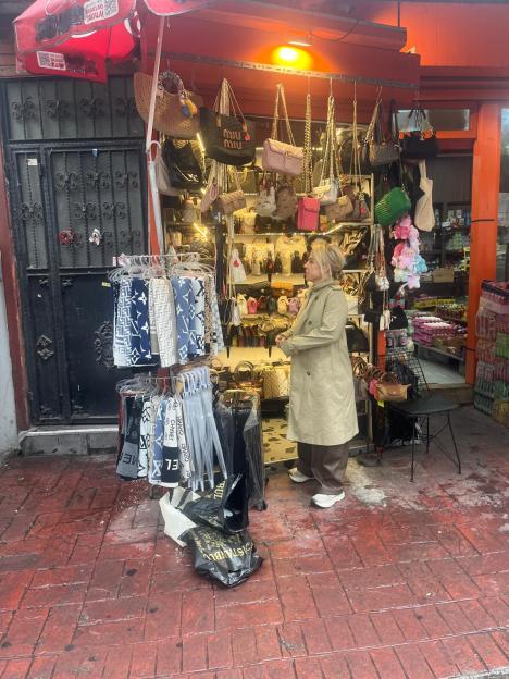 A woman stands outside a stall selling knock-off designer handbags and scarves in Istanbul.