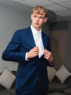 Man in a blue suit adjusting his jacket.