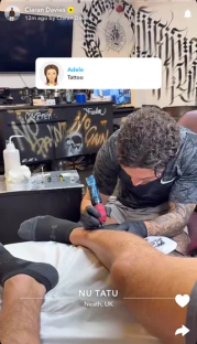 A tattoo artist inking a person's leg.
