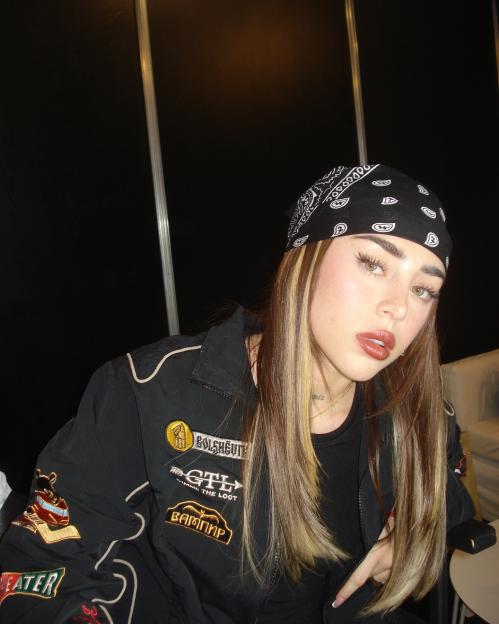 Photo of Nicki Nicole wearing a black bandana and jacket with patches.