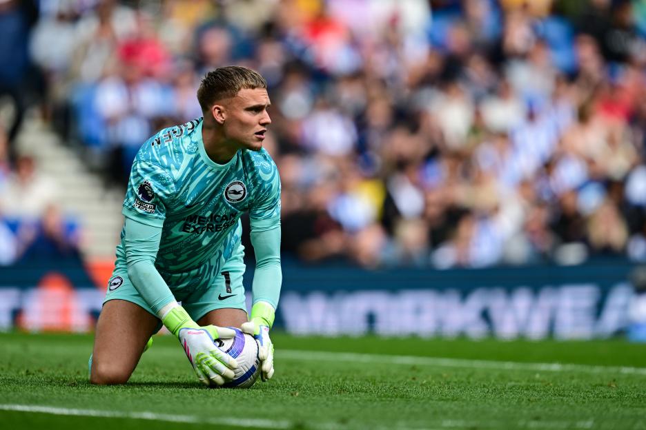 Brighton & Hove Albion goalkeeper Bart Verbruggen kneeling on the field with the ball.