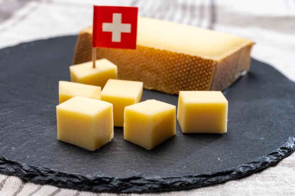 Block of Swiss cheese with cubes on a slate.
