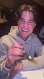 Smiling young man eating with a spoon.