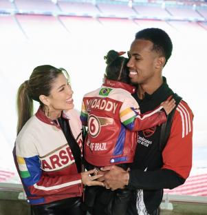 Gabriel Magalhes and Gabrielle Figueiredo with their daughter in a stadium.