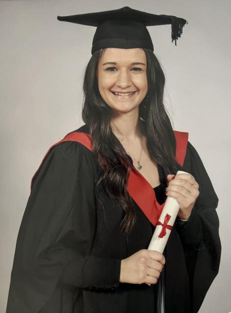 Georgia Lee in her graduation cap and gown, holding her rolled-up degree.