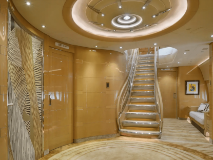 Interior of a private jet with a staircase and gold-toned walls.