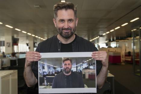 Man holding a photo of himself in an office.
