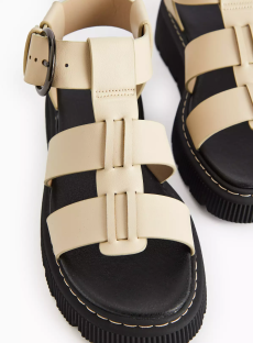 Beige leather gladiator sandals with a black sole.