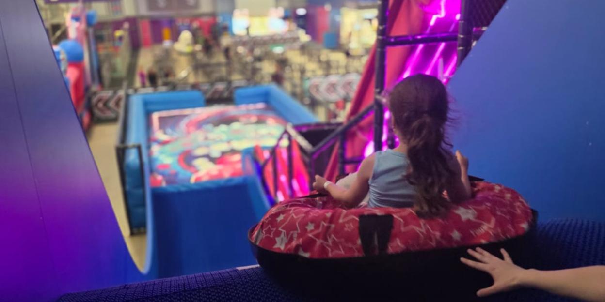 A girl in a tube sled at an indoor adventure park.
