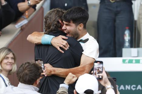 Carlos Alcaraz of Spain celebrating with his coach after a tennis match victory.