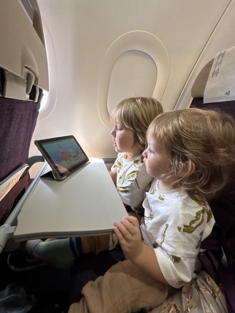 Two young boys watching a tablet on an airplane.