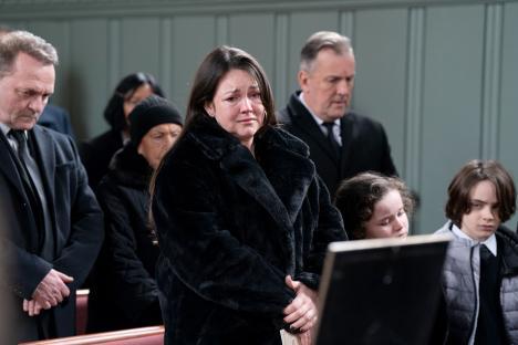 A woman cries at a funeral, surrounded by mourners.